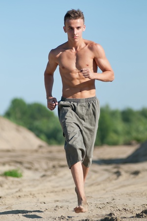 Young man running on sand beachの写真素材
