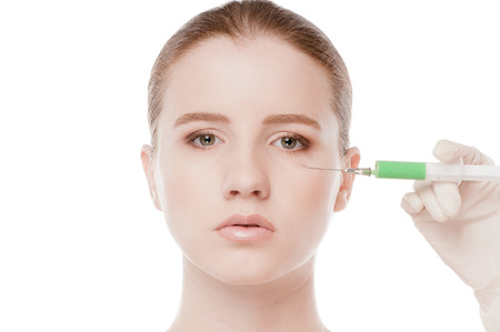 Cosmetic botox injection in the female face. Eye and eyebrow zone. Isolated on whiteの写真素材