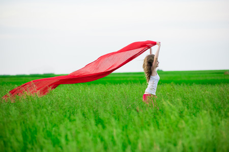 Young lady runing with tissue in green field. Beautiful happy woman walking  in the summer rural meadow. Outdoor summer portrait of pretty sport style woman jumping with fabric. Beautiful fit tan girl. Sexy slim model caucasian ethnicity outdoors.の写真素材