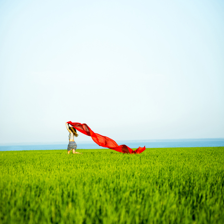 Young lady runing with tissue in green field. Beautiful happy woman walking in the summer rural meadow. Beautiful fit tan girl. Sexy slim model caucasian ethnicity outdoors.の写真素材