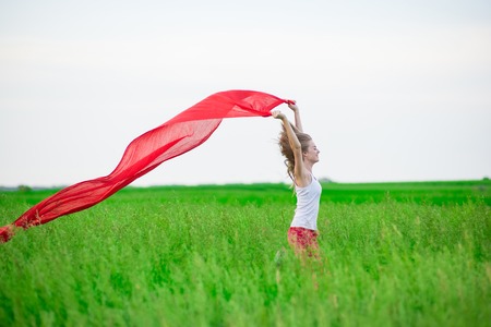 Young lady runing with tissue in green field. Beautiful happy woman walking  in the summer rural meadow. Outdoor summer portrait of pretty sport style woman jumping with fabric. Beautiful fit tan girl. Sexy slim model caucasian ethnicity outdoors.の写真素材