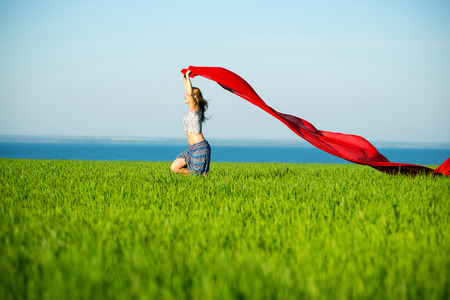 Young lady runing with tissue in green field. Beautiful happy woman walking in the summer rural meadow. Beautiful fit tan girl. Sexy slim model caucasian ethnicity outdoors.の写真素材