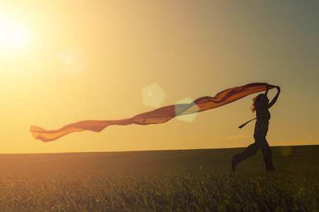 Young woman running on a rural road at sunset in summer field. Lifestyle freedom sports background. Happiness concept.の写真素材