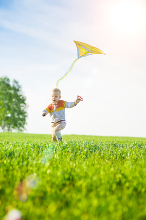 Young boy playing with his kite in a green field.の写真素材