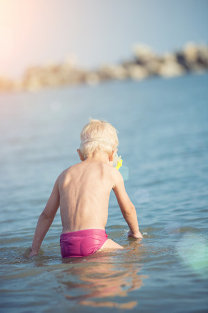 Cute little kid wearing mask and flippers for diving at sand tropical beach.の写真素材
