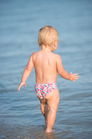 Cute baby playing on the sandy beach and in sea water.の写真素材