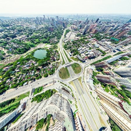 Aerial city view with crossroads and roads, houses, buildings, parks and parking lots. Sunny summer...