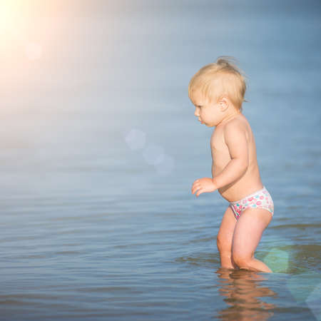 Cute baby playing on the sandy beach and in sea water.の写真素材