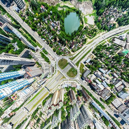 Aerial city view with crossroads and roads, houses, buildings, parks and parking lots. Sunny summer panoramic imageの写真素材