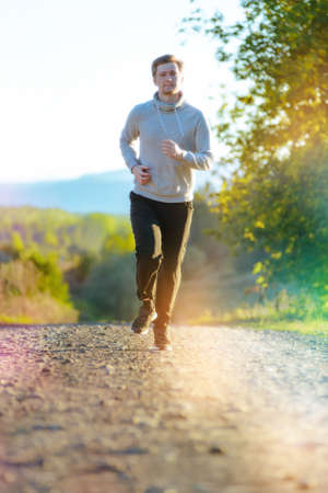 Running man jogging in rural nature at beautiful summer day. Sport fitness model caucasian ethnicity training outdoor.の写真素材