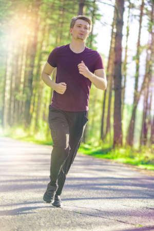 Running man jogging in city park at beautiful summer day. Sport fitness model caucasian ethnicity...