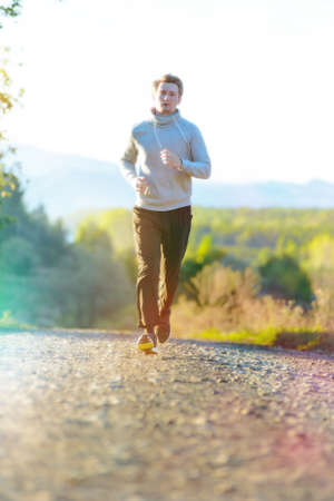 Running man jogging in rural nature at beautiful summer day. Sport fitness model caucasian ethnicity training outdoor.の写真素材
