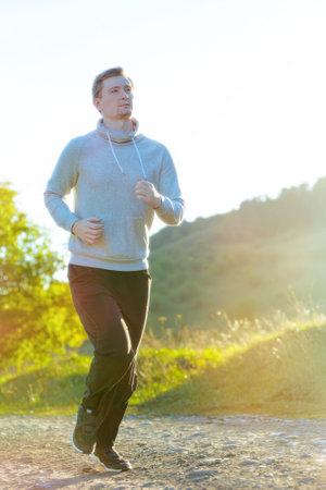 Running man jogging in rural nature at beautiful summer day. Sport fitness model caucasian ethnicity training outdoor.の写真素材