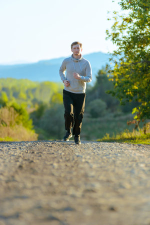 Running man jogging in rural nature at beautiful summer day. Sport fitness model caucasian ethnicity training outdoor.の写真素材