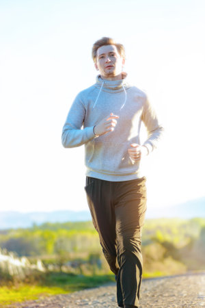 Running man jogging in rural nature at beautiful summer day. Sport fitness model caucasian ethnicity training outdoor.の写真素材