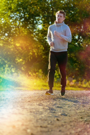 Running man jogging in rural nature at beautiful summer day. Sport fitness model caucasian ethnicity training outdoor.の写真素材