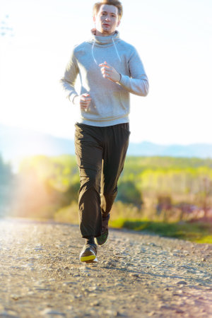 Running man jogging in rural nature at beautiful summer day. Sport fitness model caucasian ethnicity...