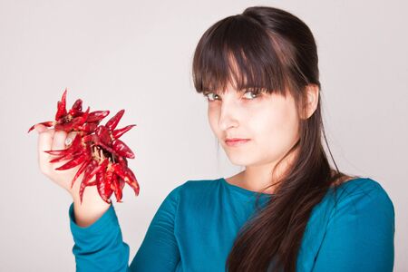 Attractive caucasion girl with chilly pepper in handsの写真素材