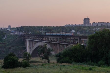 road and rail split-level bridge over the river on a background of blue sky in the city with the...