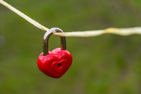 wedding decor, red lock in the shape of a heart dangling on a ropeの写真素材