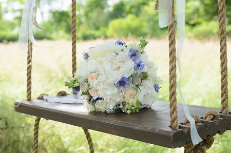 the bride's bouquet on wooden swingの写真素材