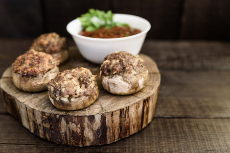 baked mushrooms with meat and sauce on a woodの写真素材