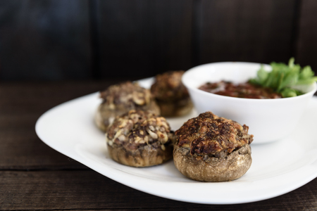 baked mushrooms with meat and sauce on a plate and woodの写真素材