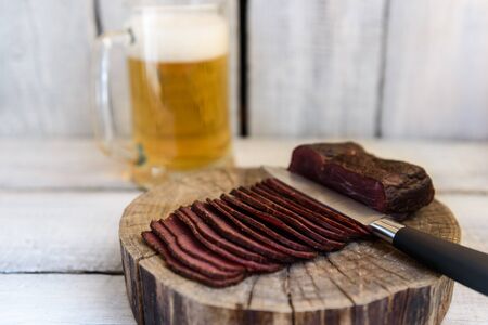 pastrami beer in a glass knife on a wooden tableの写真素材