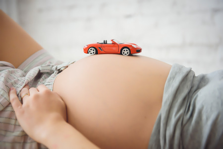midsection of pregnant woman with toy machineの写真素材