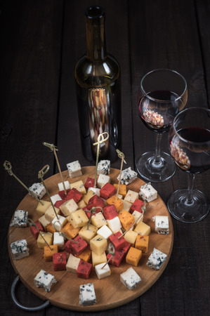 many kinds of cheeses on wooden end of a tree with reed wineの写真素材