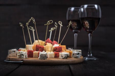many kinds of cheeses on wooden end of a tree with reed wineの写真素材