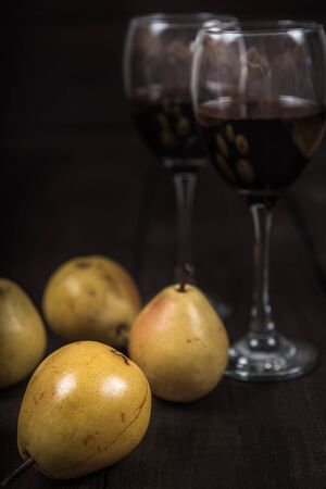 yellow pear with red wine on wooden tableの写真素材