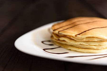 pancakes with chocolate topping and coffee cappuccino with corica on the tableの写真素材