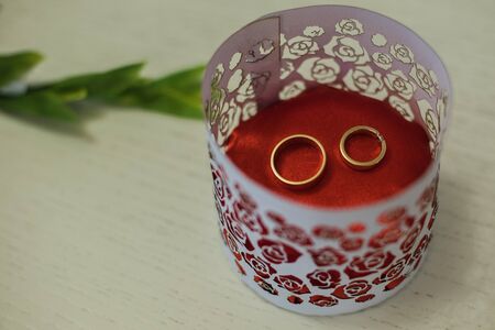 wedding rings on a red background in a carved vesselの写真素材
