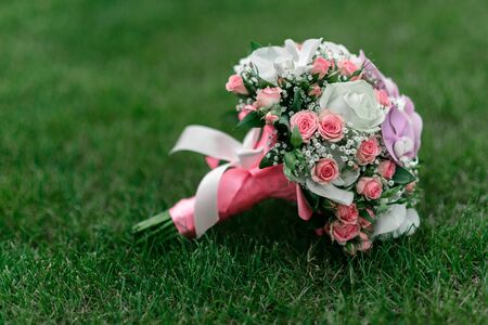 wedding bouquet on the grass, with roses, orchids and ribbonsの写真素材