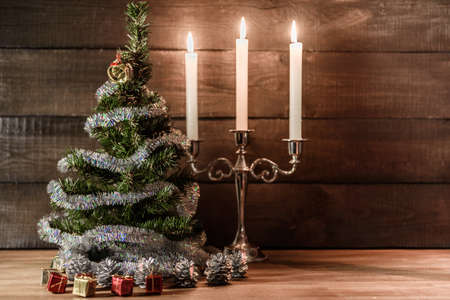 Christmas decorative tree is adorned with rain stands on the table with lit candlesの写真素材