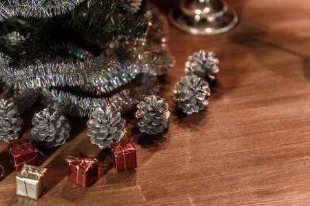 Christmas decorative tree is adorned with rain stands on the table with gifts and silver conesの写真素材