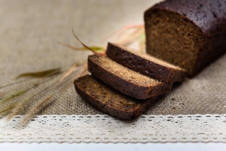black bread on burlap with ears on a white boardの写真素材