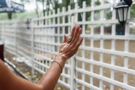 the girl held out her hand with walcom under heavy rain, water flowsの写真素材