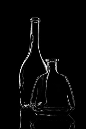 transparent bottle of brandy on a black background with reflectionの写真素材