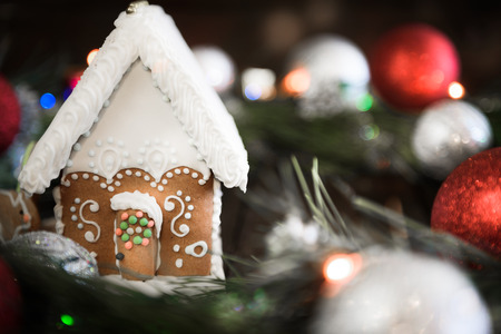the gingerbread house in the white glaze on the background of the Christmas wreath with Christmas decorations