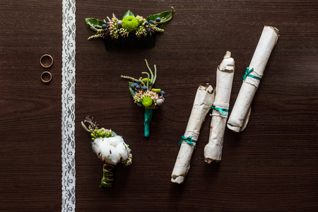 boutonniere made of cotton lying on a brown table with lace, scrolls of old parchmentの写真素材