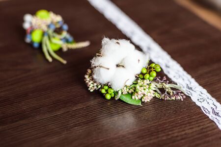 boutonniere made of cotton lying on a brown table with lace