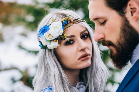 groom in a blue suit and bride in white, embroidered with blue pattern, dress on a background of green pine forests in the mountains of the Carpathiansの写真素材