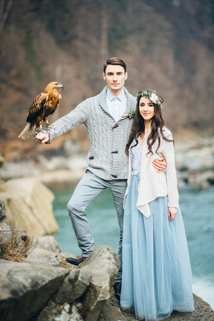 the bride and groom at the background of a waterfall with an eagle sitting on his armの写真素材