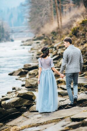 the bride and groom walking on the shore of a mountain riverの写真素材