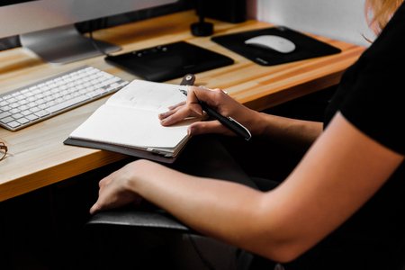 designer girl at work at the table draws on the tablet, close the keypad, printer, computerの写真素材