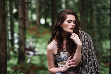 the bride wanders alone in the woods in a fur Cape and white dressの写真素材