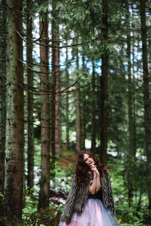 the bride wanders alone in the woods in a fur Cape and white dressの写真素材