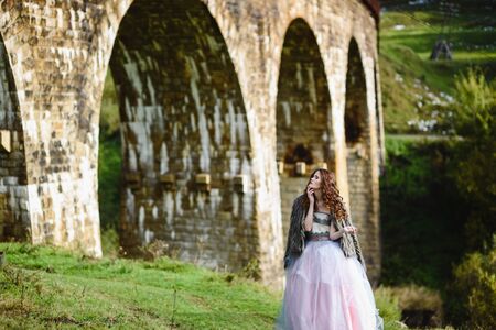 the bride walks under a bridge in a fur Cape in the Carpathiansの写真素材